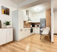 Konyha egy kétszobás lakásban fehér szekrényekkel és fa mintázatú padlóval.