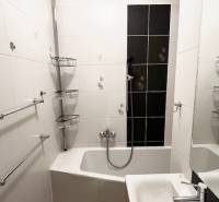 Fürdőszoba egy kétszobás lakásban zuhanyzóval és fehér csempékkel.