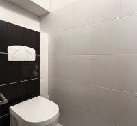 WC egy kétszobás lakásban, fehér és fekete csempékkel a falakon.