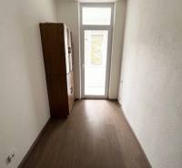 Keskeny belső tér egy kétszobás lakásban, fa dekoros padlóval és szekrénnyel.