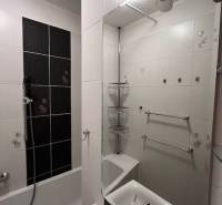 Fürdőszoba egy kétszobás lakásban káddal, mosdóval és világos csempékkel.