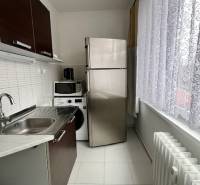 Konyha egy kétszobás lakásban fehér csempével, mosogatóval és háztartási gépekkel.