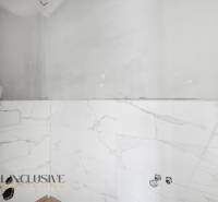 Fürdőszoba családi házban fehér márvány burkolatokkal, berendezési tárgyak nélkül.