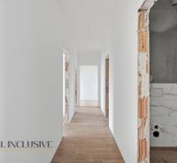 Egy családi ház folyosója fehér falakkal és fa dekorációjú padlóval.