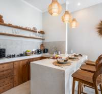 Villa konyhája stílusos fa elemekkel, bárszékekkel és függőlámpákkal.