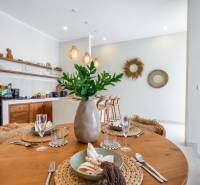 Megterített asztal egy fahatású padlójú villában és konyhasarok.