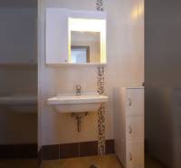 Fürdőszoba mosdóval, tükörrel és tárolószekrénnyel egy kétszobás lakásban.