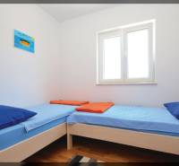 Világos szoba két egyszemélyes ággyal és fa dekorációjú padlóval.