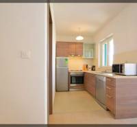 Konyha egy kétszobás lakásban fa dekorációval és készülékekkel, világos színekben.