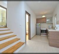 Konyha és fa dekorációjú lépcső vezet a fürdőszobához egy kétszobás lakásban.