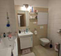 Fürdőszoba egy kétszobás lakásban káddal, mosdóval, tükörrel és világos falburkolattal.