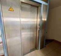 Rozsdamentes acél lift irodákban, padlón csempével.