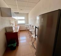 Keskeny konyha linóleummal a padlón, hűtőszekrénnyel és ablakkal az irodákban.