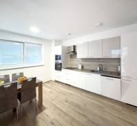 Konyha egy 3 szobás lakásban, modern konyhabútorral és fa hatású padlóval.