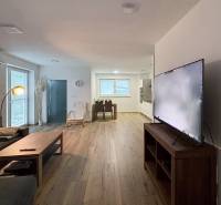 Nappali egy háromszobás lakásban kanapéval, televízióval és fa dekorációjú padlóval.