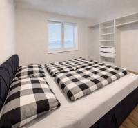 Hálószoba egy háromszobás lakásban, beépített szekrénnyel és fa dekor padlóval.