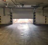 A félig nyitott garázskapu kivezet, a környezetet közvetett fény világítja meg.