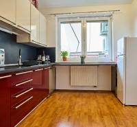 Konyha egy kétszobás lakásban piros szekrényekkel és fa dekorációjú padlóval.