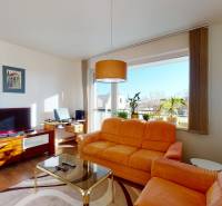 Nappali egy kétszobás lakásban narancssárga kanapéval és TV-vel, fa mintázatú padlóval.