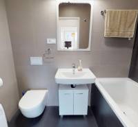 Fürdőszoba káddal, mosdóval, függesztett WC-vel és mosógéppel egy kétszobás lakásban.