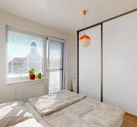 Hálószoba tolóajtós szekrénnyel és ággyal egy kétszobás lakásban, fa dekoros padlóval.