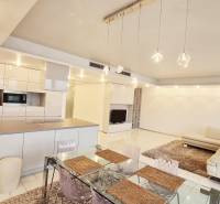 Tágas nappali egy háromszobás lakásban konyhával, étkezőasztallal és kényelmes kanapéval.