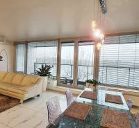 Nappali egy háromszobás lakásban világos kanapéval, asztallal és üvegezett ajtókkal.