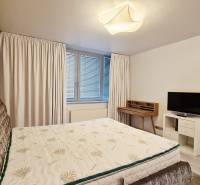 Hálószoba egy háromszobás lakásban ággyal, televízióval és íróasztallal.