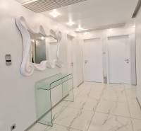 Háromszobás lakás belső tere fényes csempékkel, tükörrel és üvegasztallal.