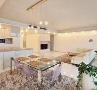 Tágas belső tér egy 3 szobás lakásban konyhával, étkezőasztallal és nappali résszel.