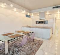 Konyha egy háromszobás lakásban étkezőasztallal és fehér csempével.