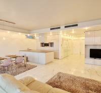 Nappali konyhaszigettel, étkezőasztallal és TV-vel egy háromszobás lakásban.