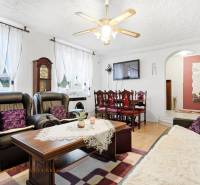 Nappali családi házban kandallóval, fekete kanapékkal és fa dekoros padlóval.