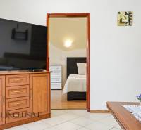 Családi ház belső tere nagy televízióval, nyitott ajtó a hálószobába, dekorációk.