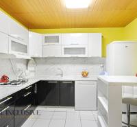 Konyha családi házban világos szekrényekkel, márványburkolattal és fehér háztartási gépekkel.