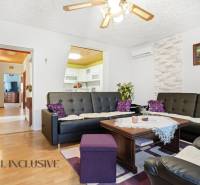 Nappali egy családi házban, fa mintázatú padlóval és fekete bőr kanapékkal.