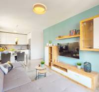 Nappali egy háromszobás lakásban konyhával, ülőgarnitúrával és fa dekorációjú padlóval.