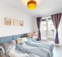 Világos hálószoba ággyal, gyerekággyal és fahatású padlóval egy háromszobás lakásban.