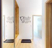 Előszoba fa dekor padlóval egy háromszobás lakásban, és felirat a falon.