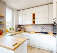 Konyha egy háromszobás lakásban fehér szekrényekkel, fa dekor padlóval és pulttal.