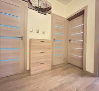 Fa padló dekoráció és világos ajtók egy kétszobás lakásban, finom világítással.