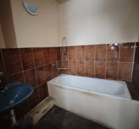 Fürdőszoba barna csempékkel, káddal és kék mosdóval egy kétszobás lakásban.