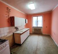 Konyha egy kétszobás lakásban narancssárga falakkal és egyszerű konyhabútorral.