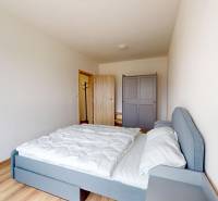 Hálószoba egy háromszobás lakásban ággyal, gardróbbal és fa dekorációjú padlóval.