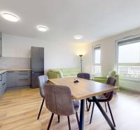 Konyha fa hatású padlóval és étkezőasztallal egy háromszobás lakásban.