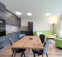 Világos konyha étkezőasztallal és kanapéval egy háromszobás lakásban, fa dekor padlóval.