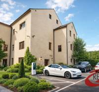 Épület Nagyugrócban zöldterülettel és elektromos autók töltőállomásával a parkolóban.