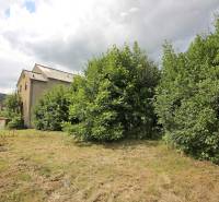 Az épület Nagyugrócon zölddel körülvéve, kilátással a dombos tájra.