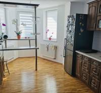 Konyha egy családi házban, fa dekoros padlóval, sötét bútorokkal és bárpulttal.