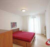 Hálószoba egy háromszobás lakásban, ággyal és fa dekoros padlóval.